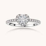 Heart-shaped halo ring with brilliant moissanite center stone surrounded by smaller crystals in sterling silver setting