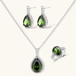 White gold plated jewelry set with green teardrop gemstones and cubic zirconia halos on cream background.