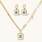Gold-plated jewelry set with white enamel square pendants and emerald CZ stones on cream background.