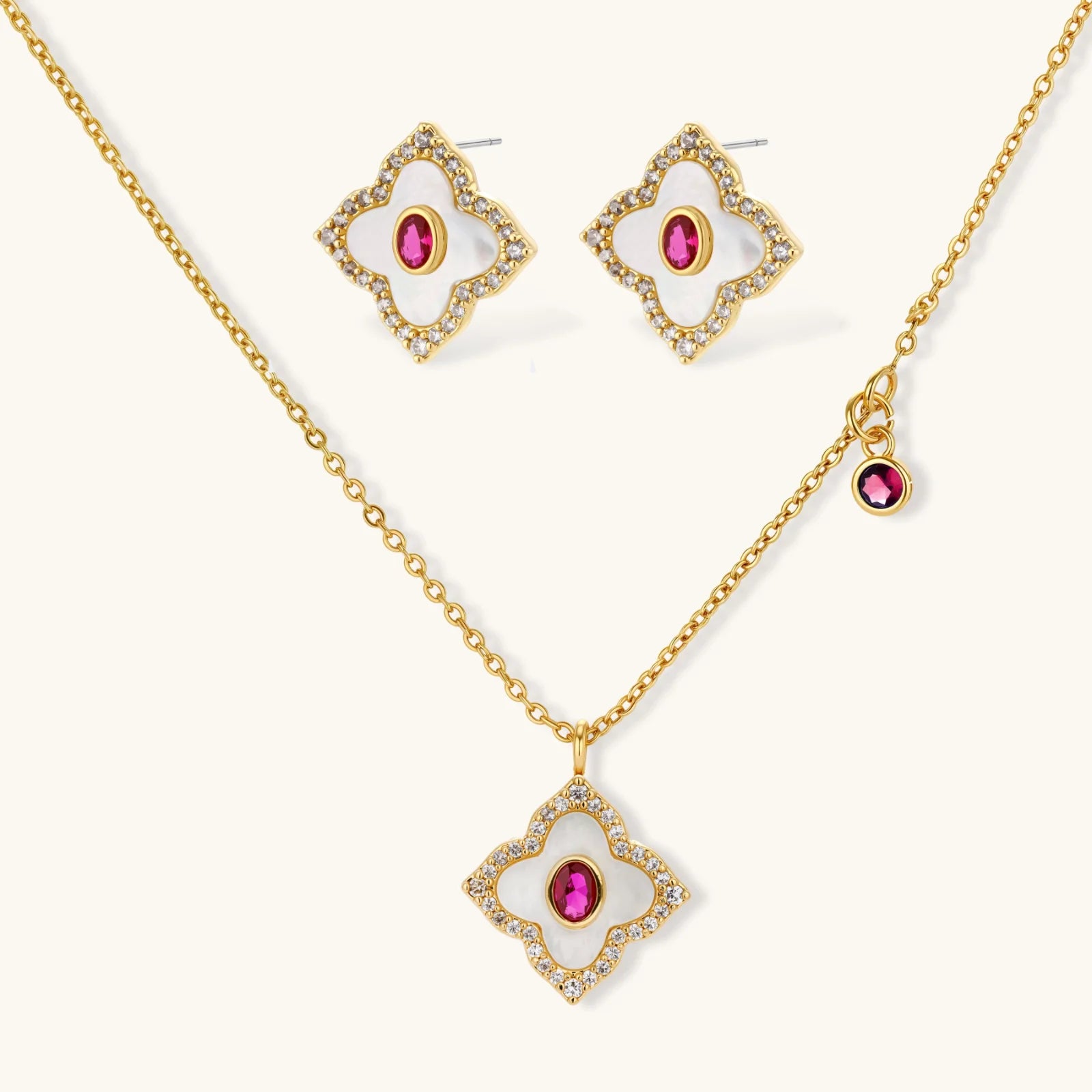 Gold-plated quatrefoil necklace and earring set with white enamel, pink cubic zirconia centers, and crystal borders
