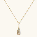 Gold-plated teardrop necklace and earrings covered in AAA cubic zirconia crystals on cream background.