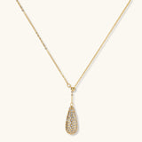 Gold-plated teardrop necklace and earrings covered in AAA cubic zirconia crystals on cream background.