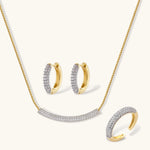 Gold-plated curved necklace, hoop earrings, and adjustable ring with pavé cubic zirconia stones on cream background.