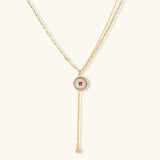 Gold-plated circular medallion necklace set with white enamel base and pink cubic zirconia accent stones