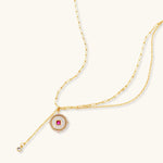 Gold-plated circular medallion necklace set with white enamel base and pink cubic zirconia accent stones