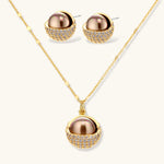 Elegant spherical pendant necklace and earrings set featuring crystal-pavé bottom half in gold or silver finish on white background.