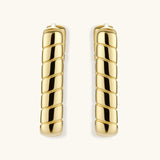 Chunky segmented gold-plated huggie hoop earrings with bamboo-inspired geometric design on white background.