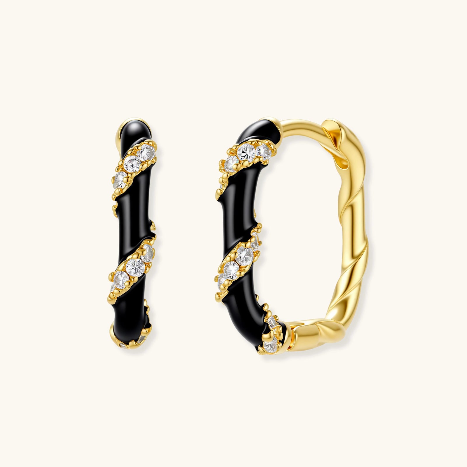 Small gold-plated hoop earrings with black enamel stripes and cubic zirconia crystals on white background.