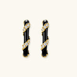 Small gold-plated hoop earrings with black enamel stripes and cubic zirconia crystals on white background.