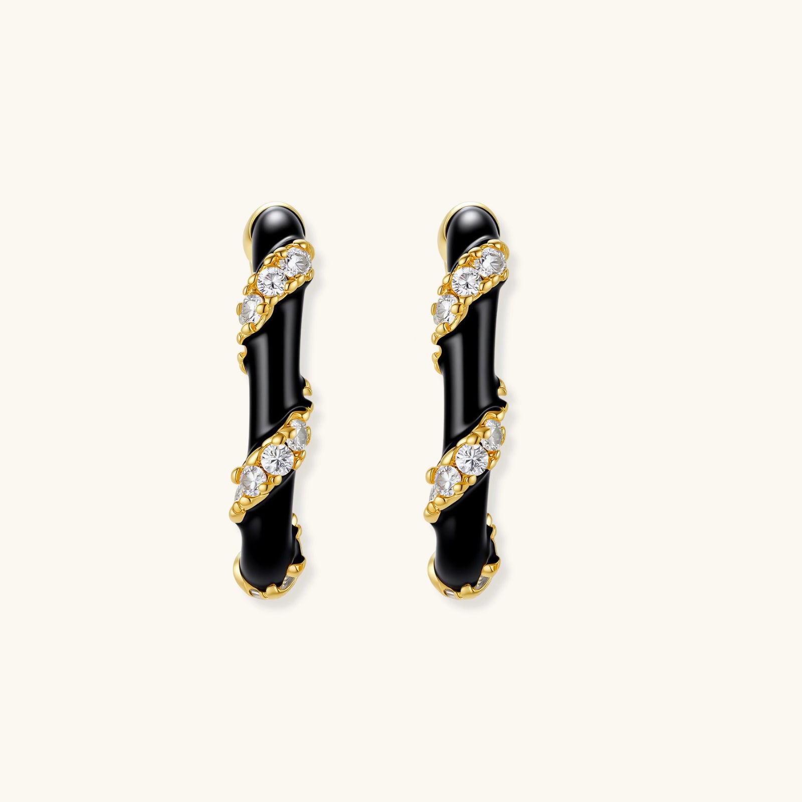 Small gold-plated hoop earrings with black enamel stripes and cubic zirconia crystals on white background.