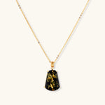 18k gold-plated necklace and earrings with green amber pendants featuring golden inclusions on cream background