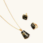 18k gold-plated necklace and earrings with green amber pendants featuring golden inclusions on cream background