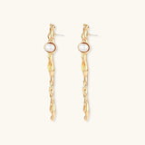 Organic twisted gold-toned drop earrings with white ABS pearls positioned near the top on cream background.