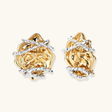 Sculptural rose-shaped stud earrings in gold with silver wire details and S925 posts on cream background.
