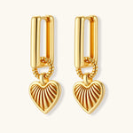 Gold-plated huggie earrings with textured heart charms featuring radiating sunburst patterns on white background.
