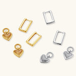 Silver huggie earrings with textured heart charms featuring radial sunburst pattern on neutral background.