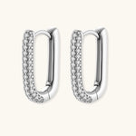 Close-up of platinum-plated sterling silver huggie hoops with pavé crystal setting on white background.