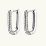 Close-up of platinum-plated sterling silver huggie hoops with pavé crystal setting on white background.