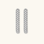 Close-up of platinum-plated sterling silver huggie hoops with pavé crystal setting on white background.