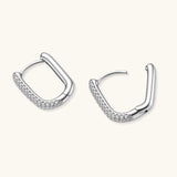 Close-up of platinum-plated sterling silver huggie hoops with pavé crystal setting on white background.