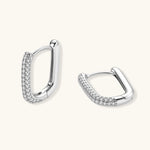 Close-up of platinum-plated sterling silver huggie hoops with pavé crystal setting on white background.