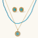 Gold-plated turquoise jewelry set with circular medallion pendant, beaded necklace, and matching stud earrings on white background