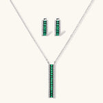 White gold plated jewelry set with emerald green rectangular stones and clear crystals in geometric rows on white background.