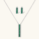 White gold plated jewelry set with emerald green rectangular stones and clear crystals in geometric rows on white background.