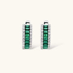 White gold plated jewelry set with emerald green rectangular stones and clear crystals in geometric rows on white background.