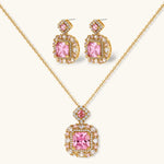 Ornate gold-plated jewelry set with rose pink zirconia center stones and crystal accents on cream background.