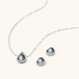 White gold plated spherical jewelry set with zirconia crystal pavé and dark lustrous centers on neutral background.