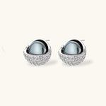 White gold plated spherical jewelry set with zirconia crystal pavé and dark lustrous centers on neutral background.