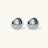 White gold plated spherical jewelry set with zirconia crystal pavé and dark lustrous centers on neutral background.