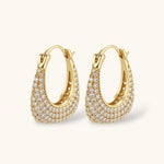 Gold-plated hoop earrings fully covered in sparkling zircon crystals with hinged closure on neutral background