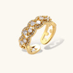 Adjustable gold-plated ring with multiple crystal clusters in intricate chain design on cream background.