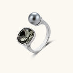 Modern adjustable ring with smoky zircon stone and metallic sphere in platinum-plated copper finish on neutral background.