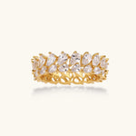 Adjustable gold-plated ring with double-row pear-shaped cubic zirconia stones in geometric pattern on cream background.