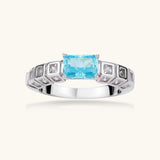 Geometric silver-plated ring with rectangular aqua cubic zirconia center and square crystal details on adjustable band.