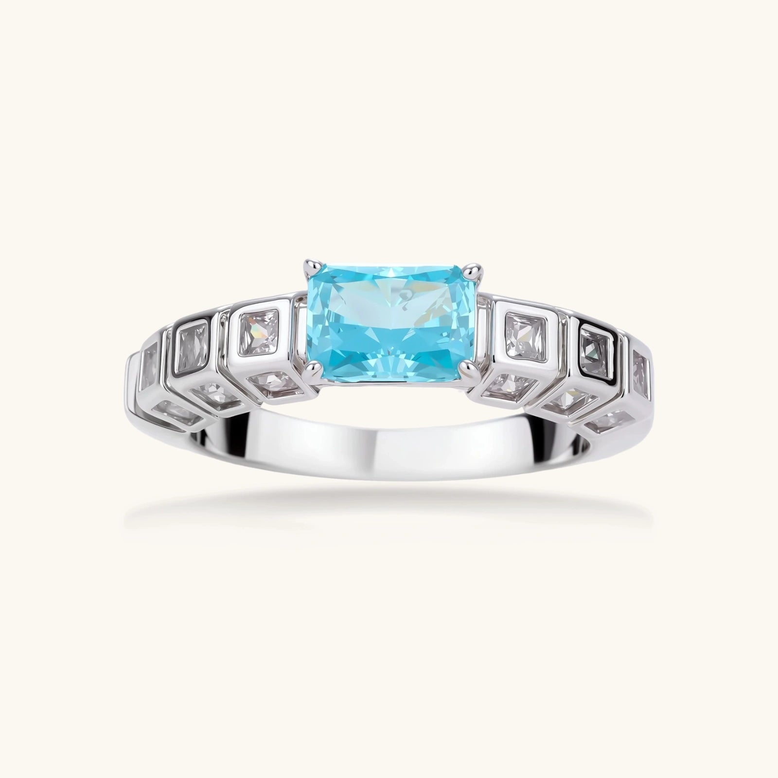Geometric silver-plated ring with rectangular aqua cubic zirconia center and square crystal details on adjustable band.
