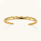 Polished 18K gold plated cuff bracelet with cubic zirconia set in star motifs on a cream background.