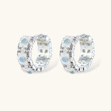 Silver-plated hoop earrings featuring delicate daisy flowers with powder blue centers and crystal accents on white background.