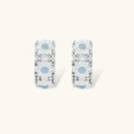 Silver-plated hoop earrings featuring delicate daisy flowers with powder blue centers and crystal accents on white background.
