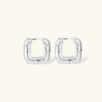 Close-up of ridged silver-plated hoop earrings with embedded crystal details on white background.