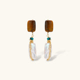 Gold-plated drop earrings with amber stones, teal beads, and wire-wrapped baroque pearls on cream background.