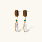 Gold-plated drop earrings with amber stones, teal beads, and wire-wrapped baroque pearls on cream background.