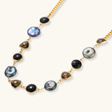18k gold-plated chain necklace featuring lustrous baroque pearls, black onyx rounds, and smoky quartz triangular stones on white background.