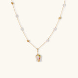 Delicate 18k gold-plated chain with baroque pearls and colorful enamel pendant featuring blue, pink accents on cream background.
