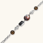Chain bracelet with amber stones, baroque pearl, and dark rectangular stone on white gold-plated copper base.