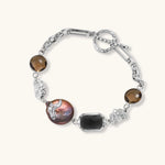 Chain bracelet with amber stones, baroque pearl, and dark rectangular stone on white gold-plated copper base.